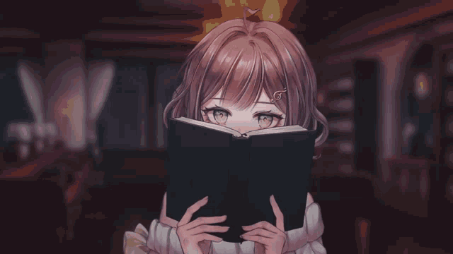 a girl is covering her face with a book and smiling