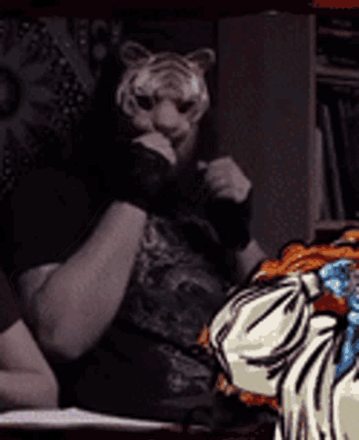 a man wearing a tiger mask is sitting next to a zebra statue