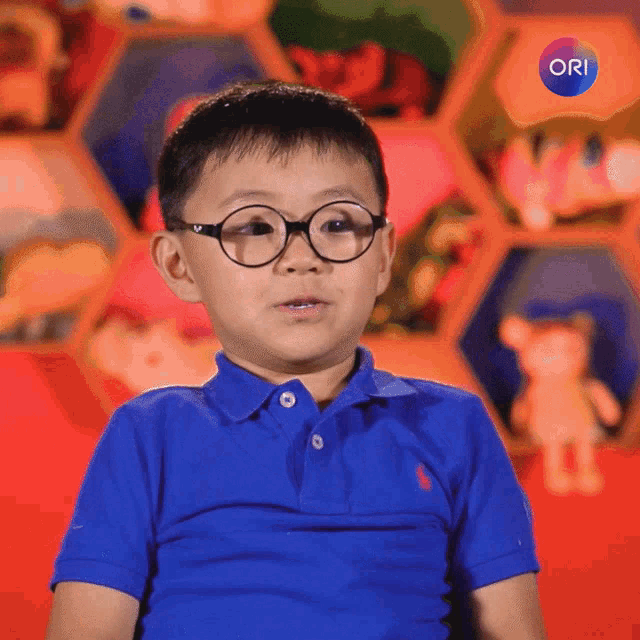 a young boy wearing glasses and a blue polo shirt with the word ori on the bottom