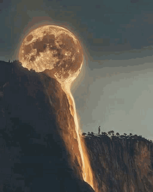 a full moon is behind a waterfall on a mountain .