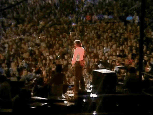 a man singing into a microphone in front of a large crowd