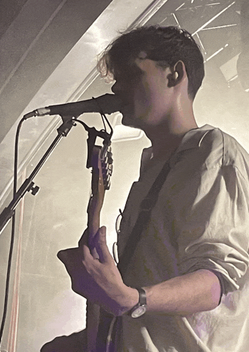 a man sings into a microphone while playing a guitar