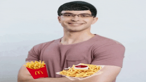 a man holding a tray of french fries next to a mcdonald 's box of french fries