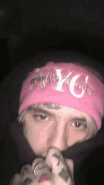 a close up of a person wearing a pink beanie and covering their face .