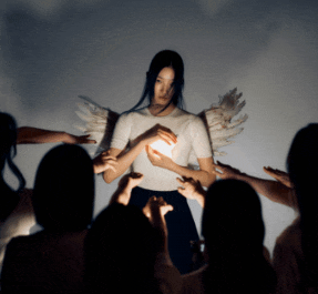 a woman with angel wings is surrounded by a crowd of people