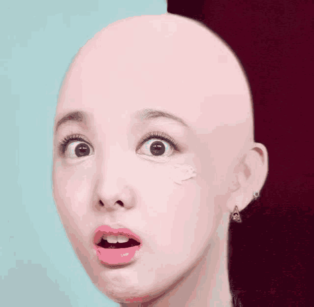 a close up of a woman 's face with a shaved head .