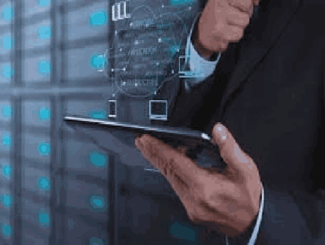 a man in a suit is holding a tablet computer in his hands in a server room .