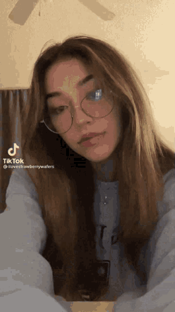 a girl wearing glasses has a tiktok on her shoulder