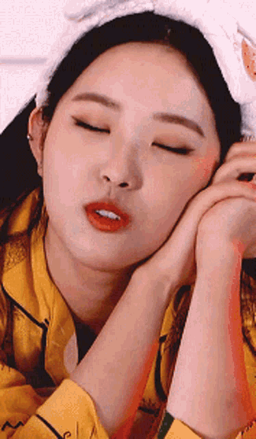 a woman with her eyes closed wearing a yellow shirt and a white headband
