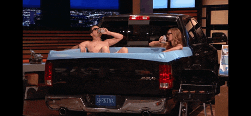 a man and a woman are in a tub in the back of a truck