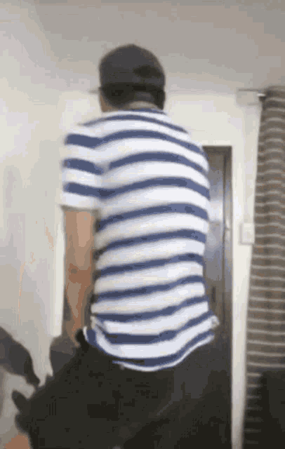 a man in a blue and white striped shirt is standing in a room