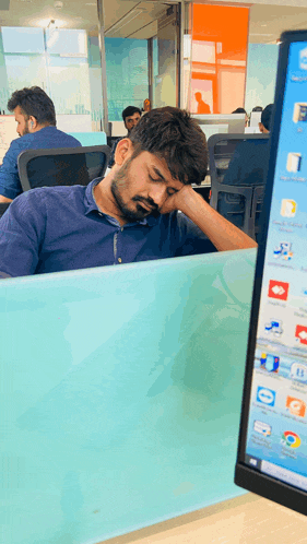 a man sleeping at a desk in front of a computer screen that says skype on it