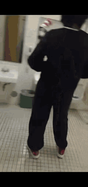 a person is standing in a bathroom with a sink and toilet