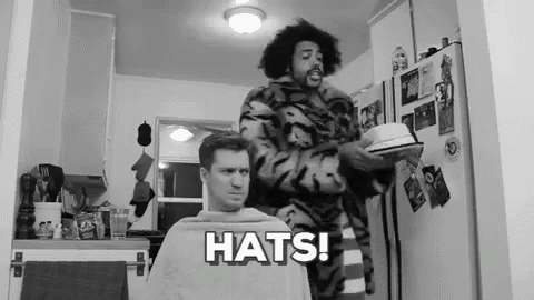 a black and white photo of a man getting his hair cut by another man with the words hats on the bottom