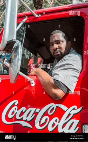 a man is sitting in the driver 's seat of a red coca-cola truck