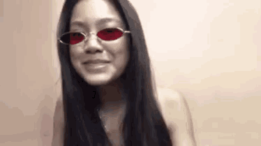 a woman wearing a pair of red sunglasses is smiling .