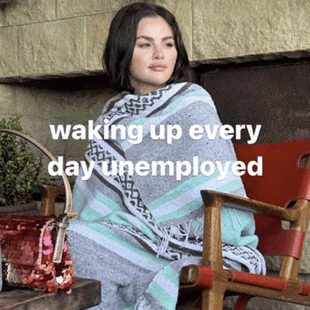 a woman wrapped in a blanket is sitting in a chair with the words waking up every day unemployed behind her