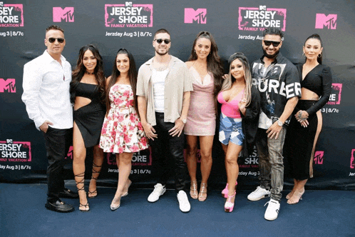 a group of people standing in front of a wall that says jersey shore