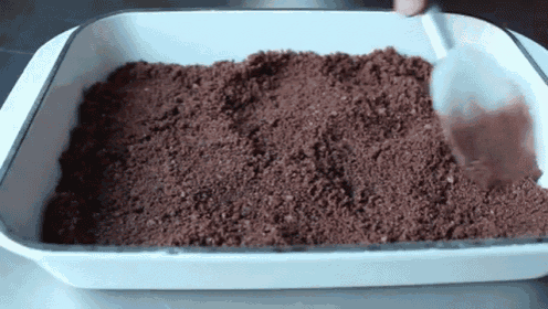 a white pan filled with chocolate crumbs and a spatula