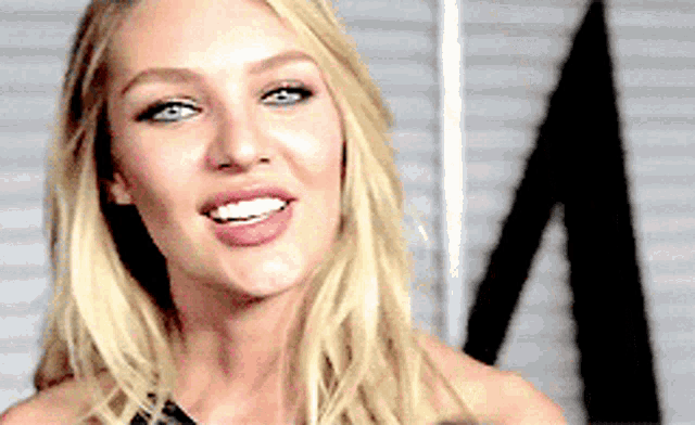 a woman with blonde hair and blue eyes is smiling and looking at the camera