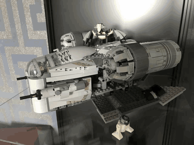 a lego model of a space ship is sitting on a glass shelf