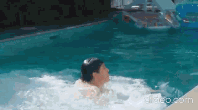 a man is swimming in a swimming pool with a float in the background .