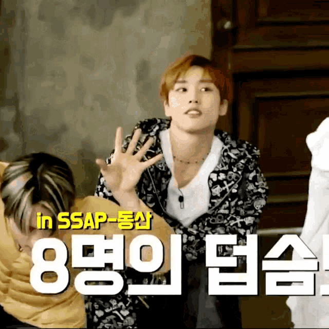 a man in a black and white jacket is standing in front of a sign that says in ssap-dongsan