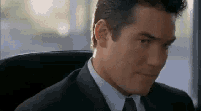 a man in a suit and tie is sitting in an office chair looking at the camera .