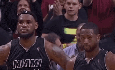 two miami heat basketball players are standing next to each other in front of a crowd during a game .