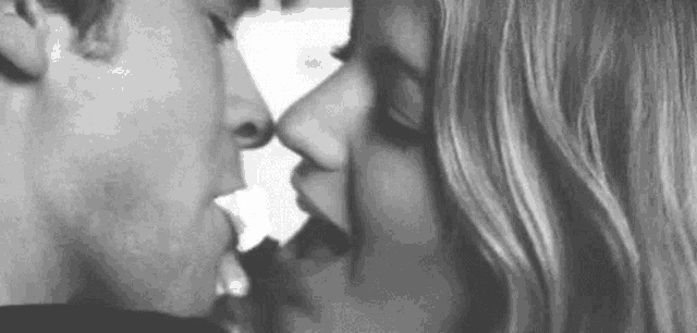 a black and white photo of a man and woman kissing each other .