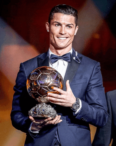 a man in a suit and bow tie holds a soccer ball