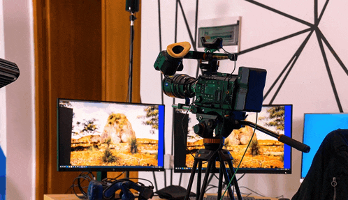 a video camera is sitting on a tripod in front of two computer monitors