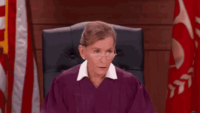 a female judge wearing glasses is sitting in a courtroom