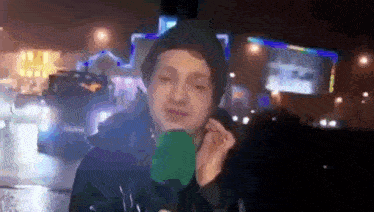 a man wearing a black hat and a green microphone talking on a cell phone .