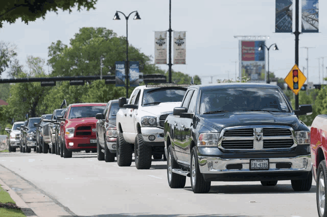 a row of pickup trucks are lined up on a street with a dodge truck with a texas license plate