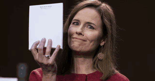 a woman in a red jacket holds up a piece of paper that says united states senate on it