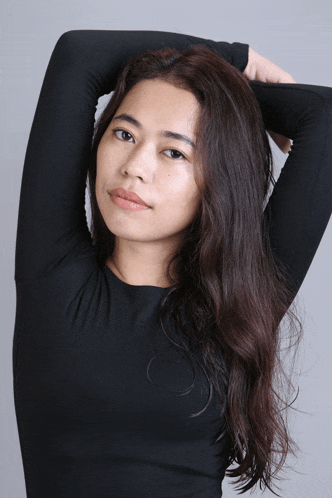 a woman wearing a black shirt with her arms behind her head