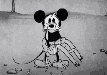 mickey mouse is crying in a black and white cartoon while holding a person 's leg .