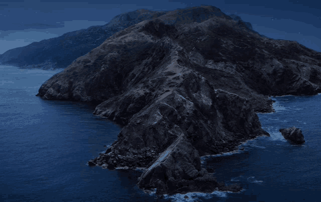 a dark cliff surrounded by water and mountains