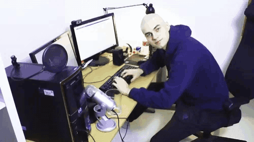 a man in a blue hoodie is typing on a keyboard