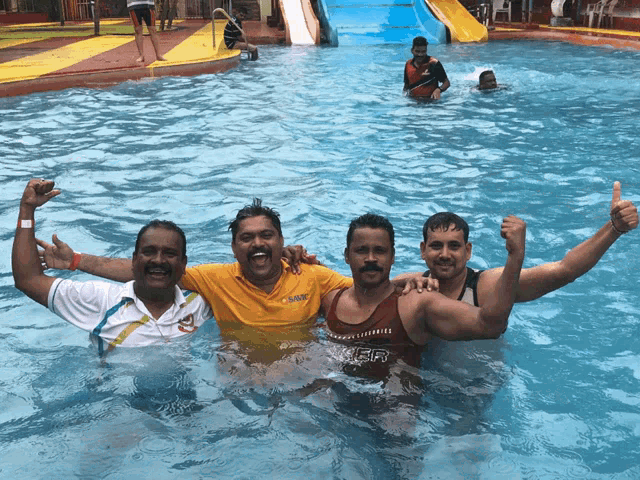 a man in a red tank top with the word tiger on it poses with two other men in a swimming pool