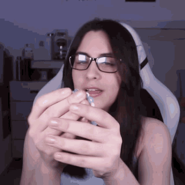 a woman wearing glasses is holding a blue object in her hands