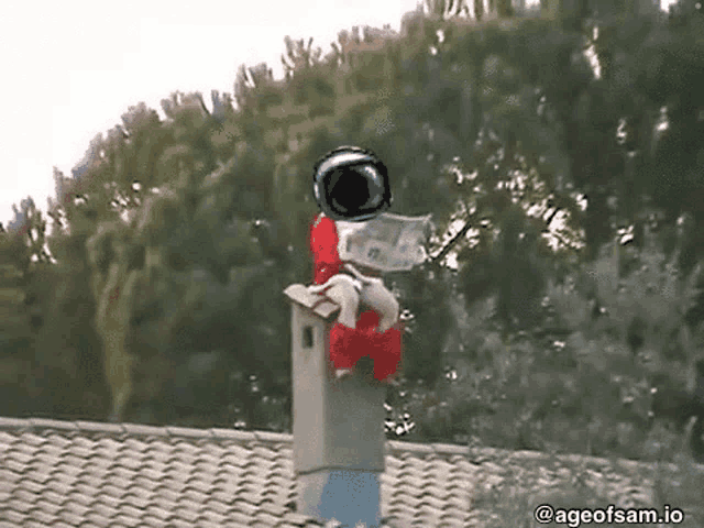 a person in an astronaut costume is sitting on top of a chimney reading a newspaper .