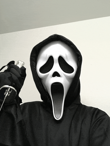 a person wearing a scream mask is holding a cellphone