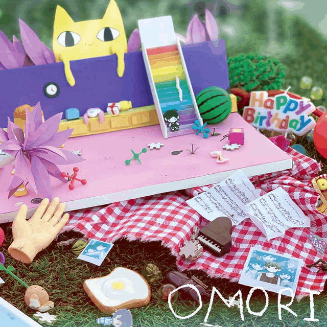 a happy birthday sign sits on a picnic blanket surrounded by toys