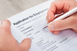a person is filling out an application for employment form with a pen .