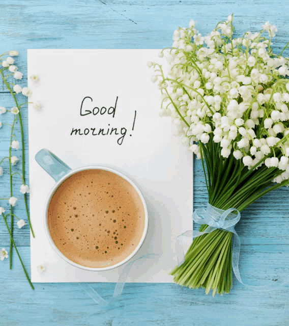 a bouquet of lily of the valley flowers sits next to a cup of coffee and a note that says good morning