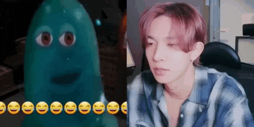 a man in a plaid shirt is sitting in front of a computer next to a green balloon with smiley faces on it .