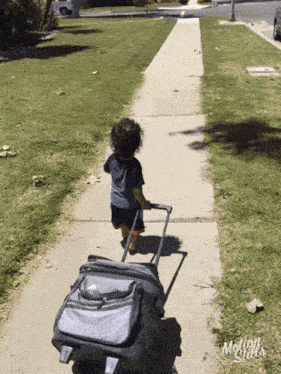 a little boy pulling a suitcase down a sidewalk with the words motion girls written on the bottom