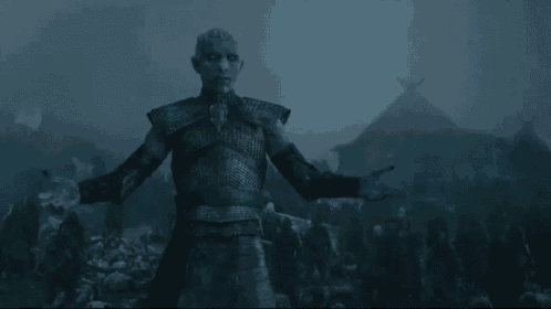 a man in armor is standing in the dark with his arms outstretched .